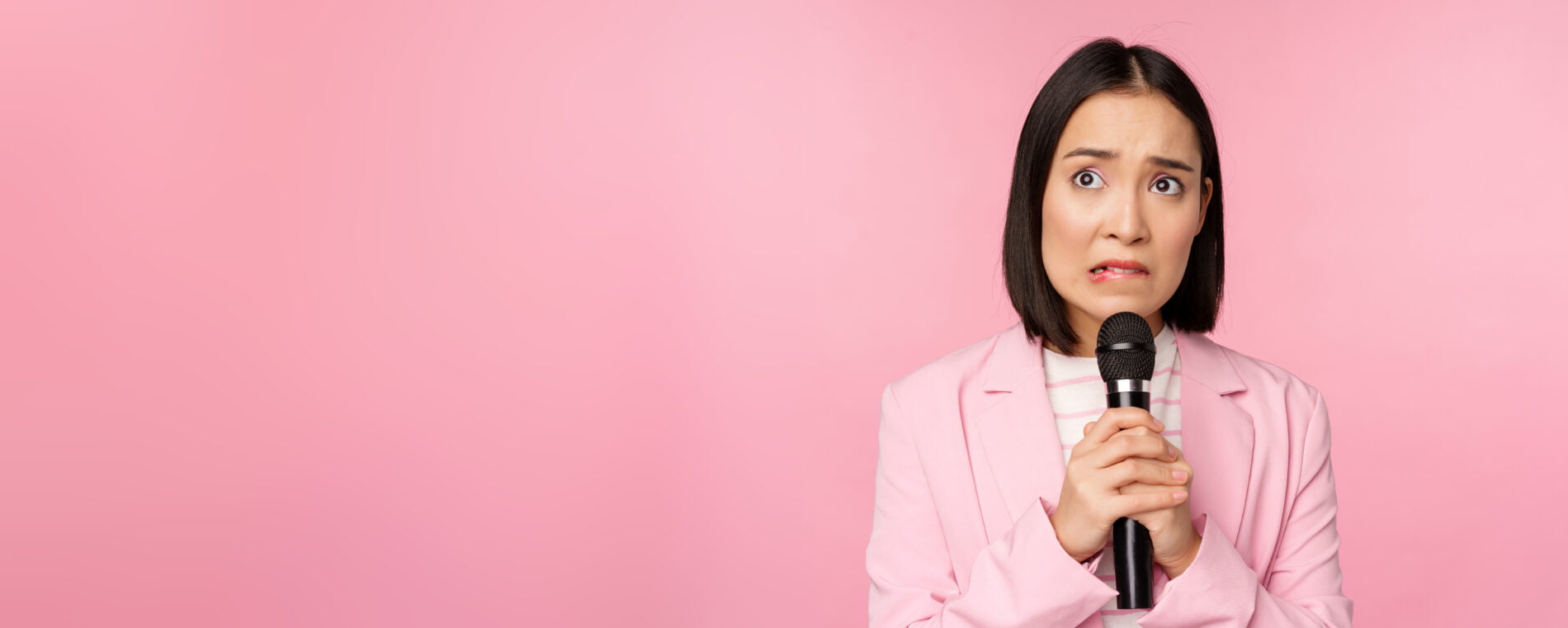 anxious asian lady suit talking public giving speech with microphone conference looking scared standing pink background 74% of People Fear Public Speaking: Here's How to Beat Glossophobia