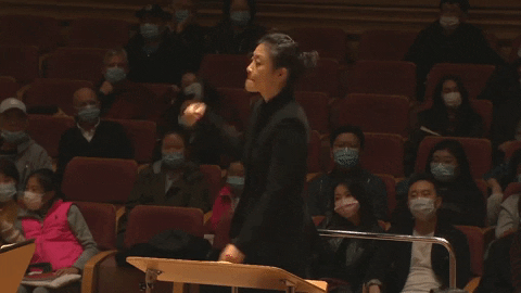 a female orchestra conductor in all black suit in action