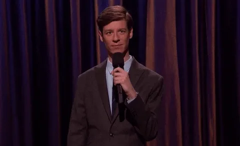 Speaking in Public: How to Use the Power of the Pause for Memorable Talks 9 Man in suit on stage holding a microphone taking a pause.