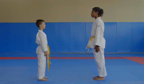 a boy and female instructor bowing in judo setup