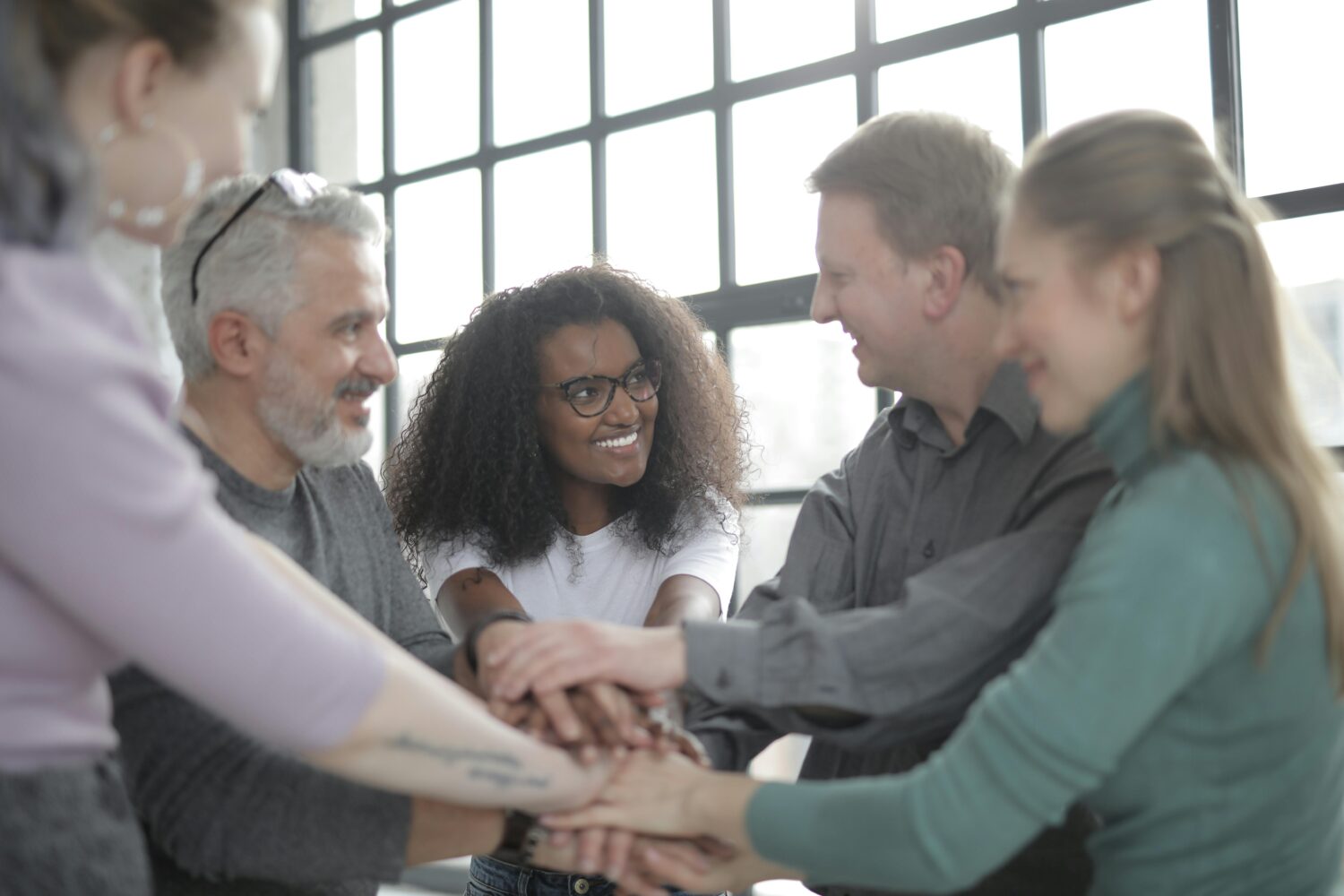 happy-multiracial-coworkers-uniting-hands-after-making-decision