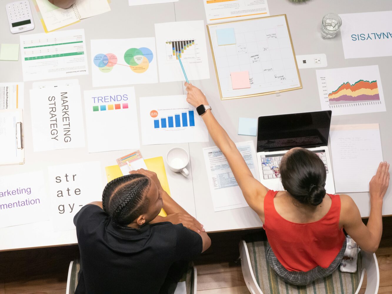 Visual aids on the table with a woman pointing at it and a a man onlooking