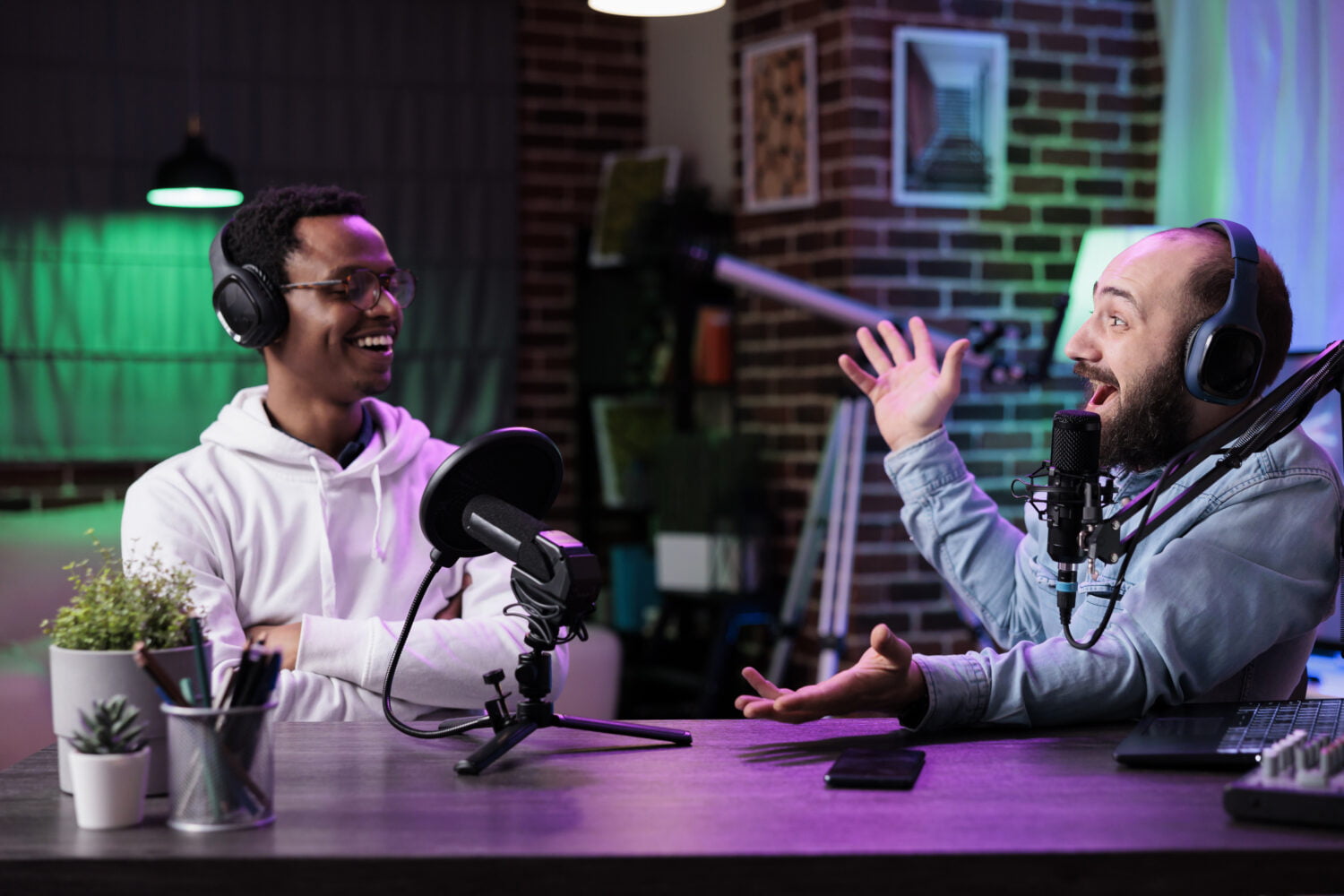 POV of male bloggers vlogging podcast talk on camera, using streaming equipment in studio with neon lights. Content creators having fun filming online episode for social media.